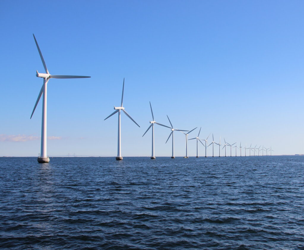 Perspective line of ocean wind mills with dark water and sky